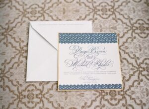 Hand Calligraphy Wedding Invitation Mounted on Gold Paper with Blue Swirls